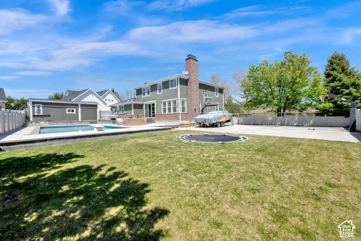 Expansive backyard featuring a rectangular swimming pool, integrated spa, and large shed
