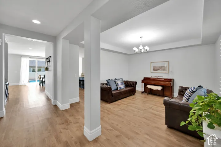 Open concept living space with recessed lighting, wood-finish flooring, and a tray ceiling with a chandelier