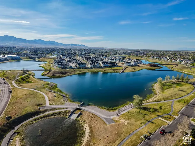 Expansive lake with surrounding land, pedestrian pathways, and a mountainous backdrop