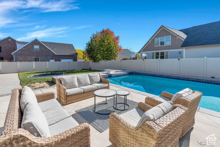 View of pool featuring outdoor seating, a fenced backyard, patio surround