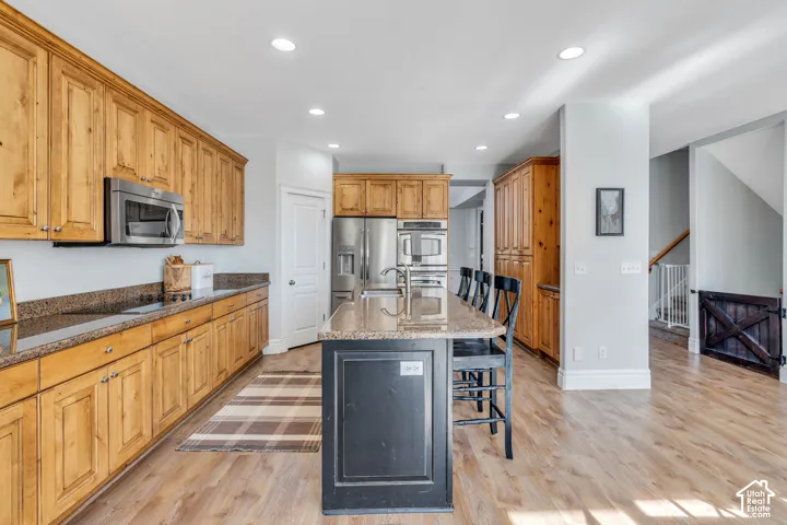 Kitchen featuring a kitchen bar, dual tone cabinets, stainless steel appliances, a kitchen island with sink