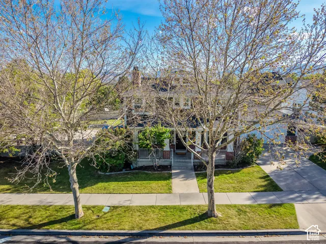 Traditional-style residence with brick accents, an inviting front porch, and mature trees