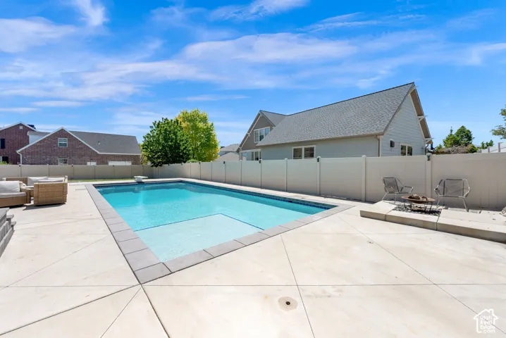 Rectangular in-ground swimming pool with an integrated shallow area, surrounded by concrete decking