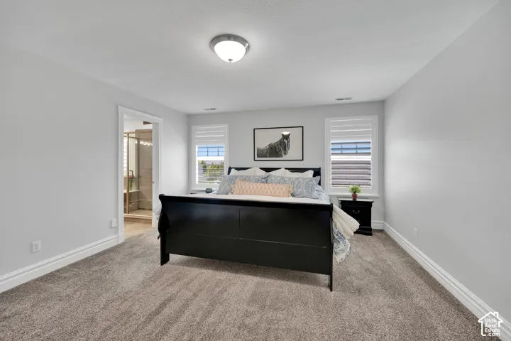 Carpeted flooring, recessed lighting, dual windows, and an attached en-suite bathroom with a glass-enclosed shower