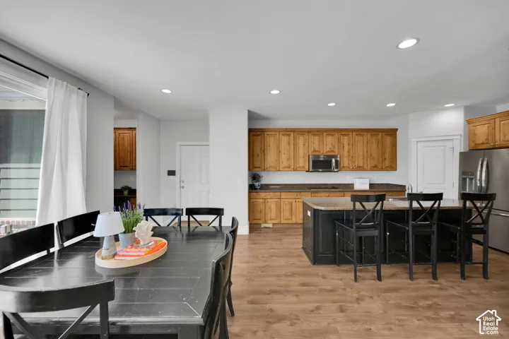 LVP flooring throughout, stainless steel refrigerator, stainless steel microwave, wood cabinetry, and recessed lighting