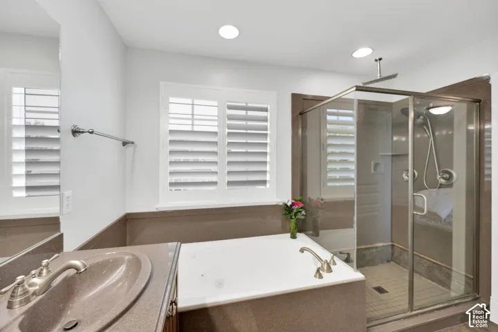 En-suite primary bath, glass-enclosed shower, dual windows with shutters, recessed lighting