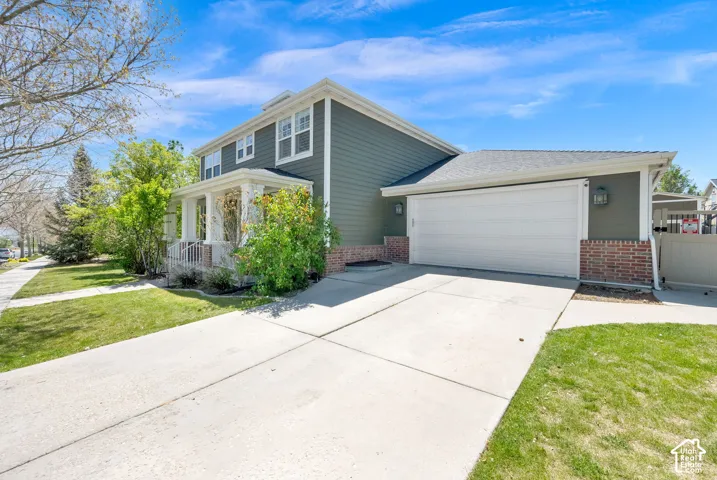 Two-story residence featuring a covered front porch, attached garage, concrete driveway, and brick accent siding