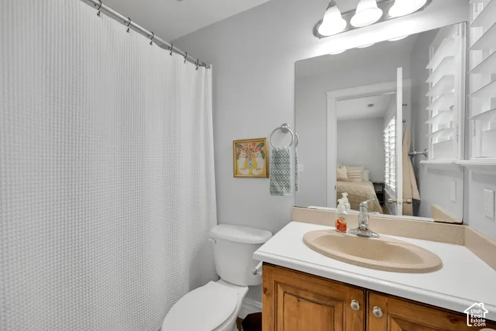 En-suite bathroom featuring a wood-finish vanity with a built-in sink, wall-mounted mirror, and vanity lighting