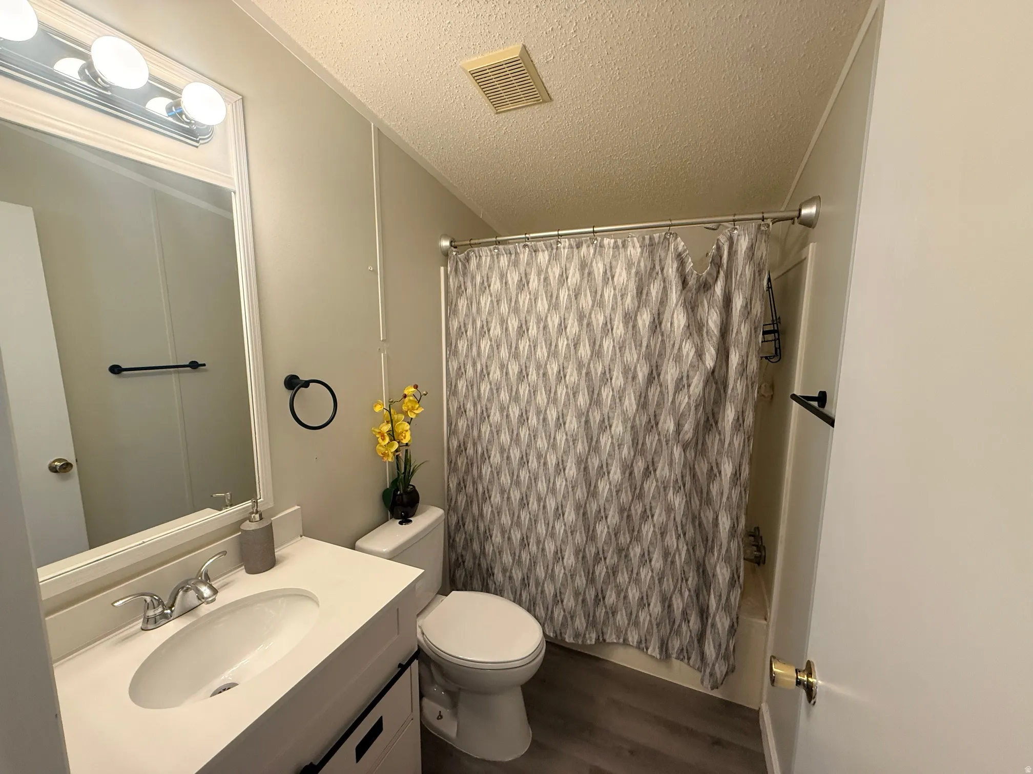 Bathroom featuring a vanity with a white countertop and integrated sink, chrome faucet, and overhead three-bulb vanity light