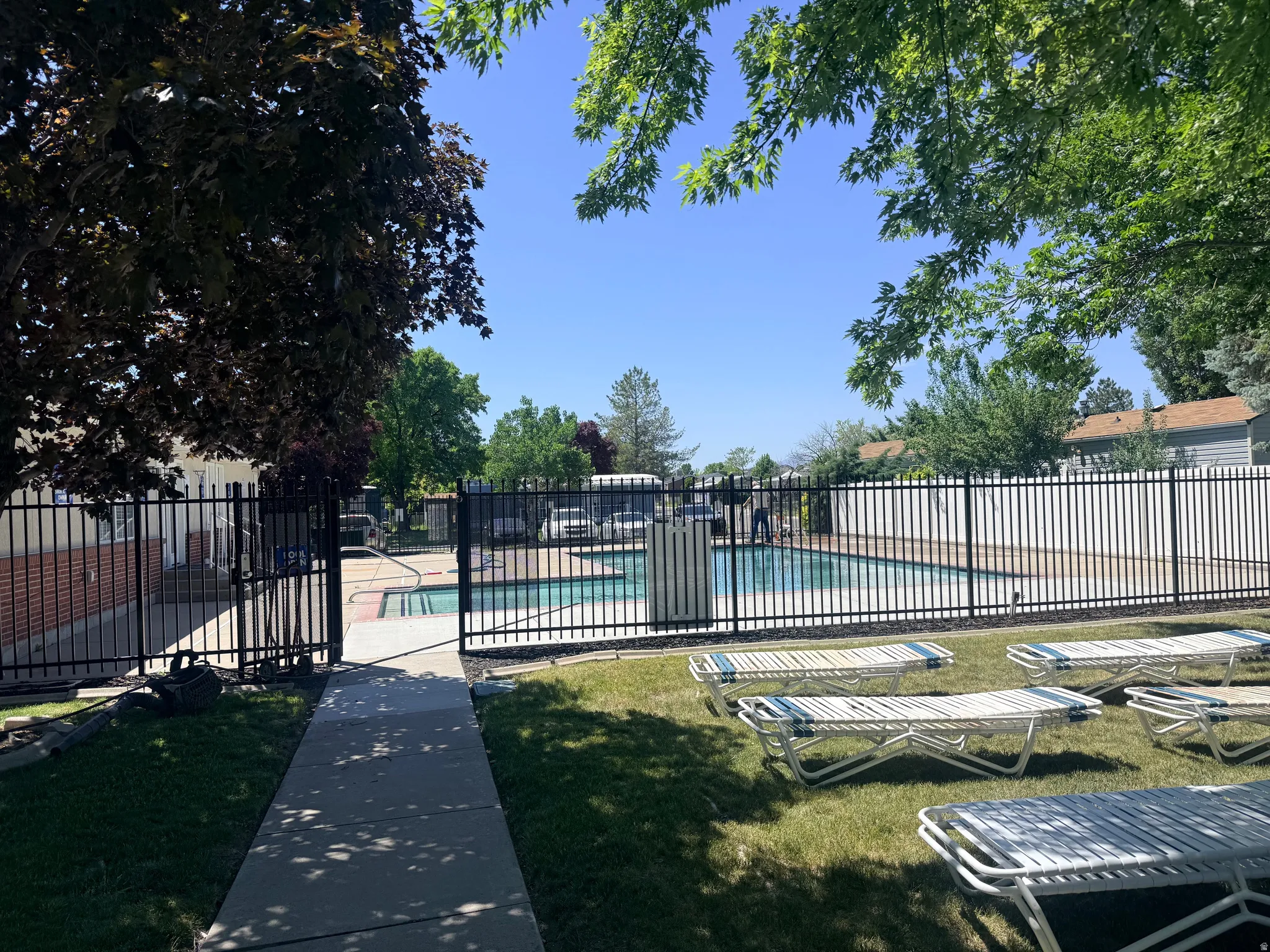 Outdoor swimming pool with surrounding black metal fencing and an adjacent grass area
