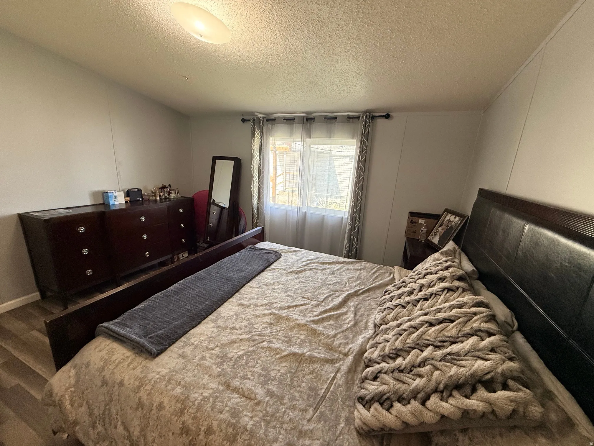 Bedroom featuring light gray wall paneling and wood-finish flooring