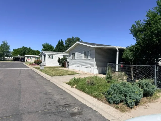 White siding exterior with a covered front porch and chain-link fencing