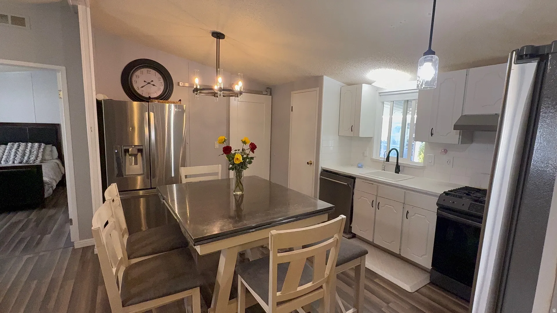 Contemporary kitchen featuring wood-finish flooring, white cabinetry, and a subway tile backsplash