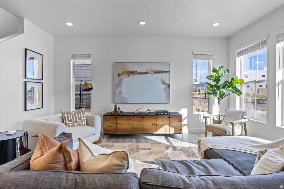 Open-concept living space featuring high ceilings, recessed lighting, wood-finish flooring, and multiple large windows with blinds