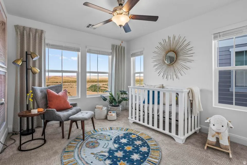 Carpeted room featuring multiple large windows, a ceiling fan with integrated lighting, and a neutral color palette