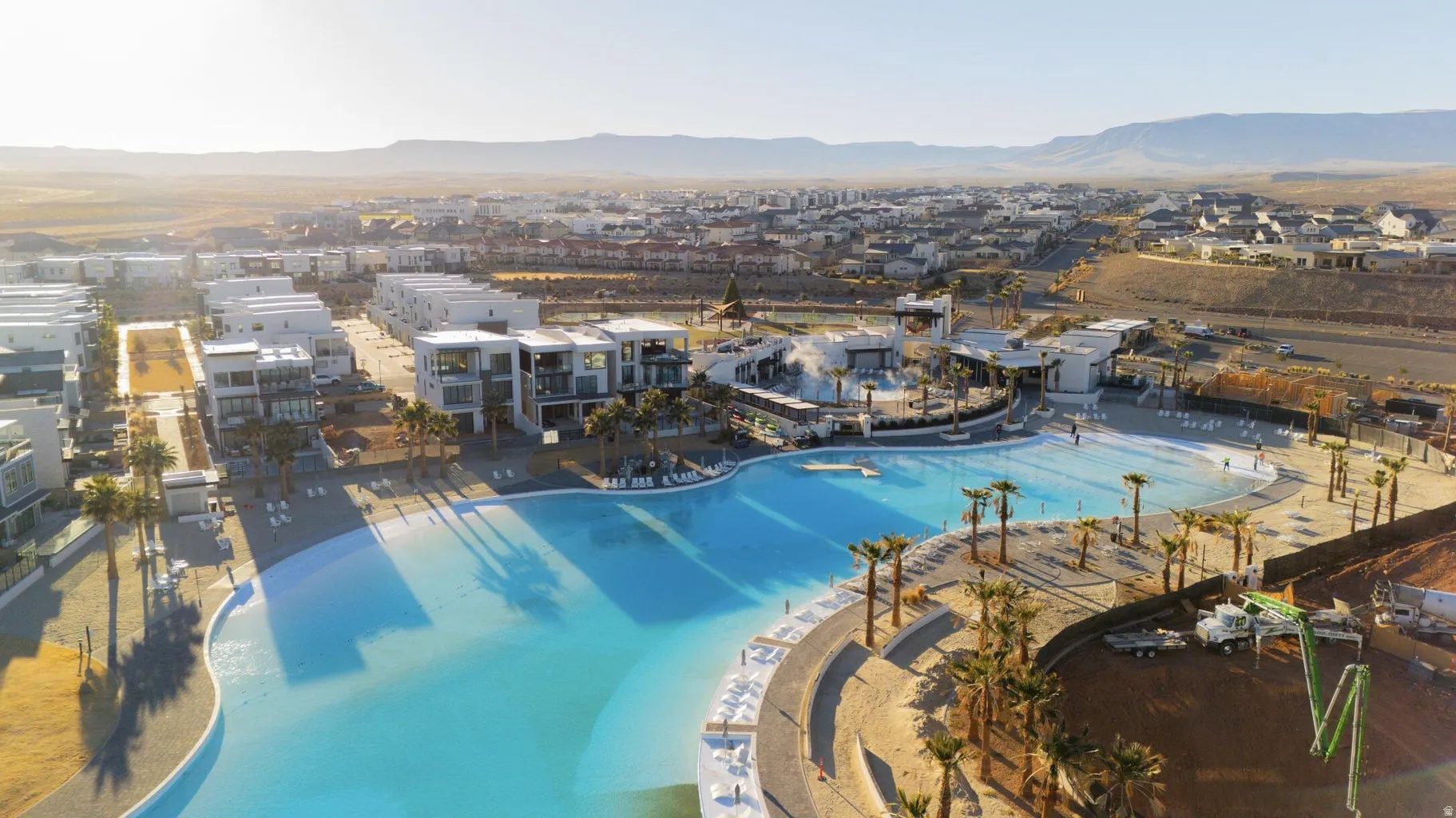 Expansive community lagoon with surrounding residences, resort-style amenities, and distant mountain ranges