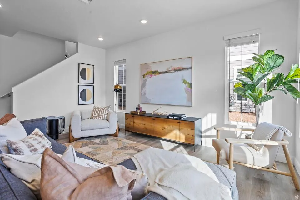 Open-concept living space featuring wood-finish flooring, recessed lighting, and large windows