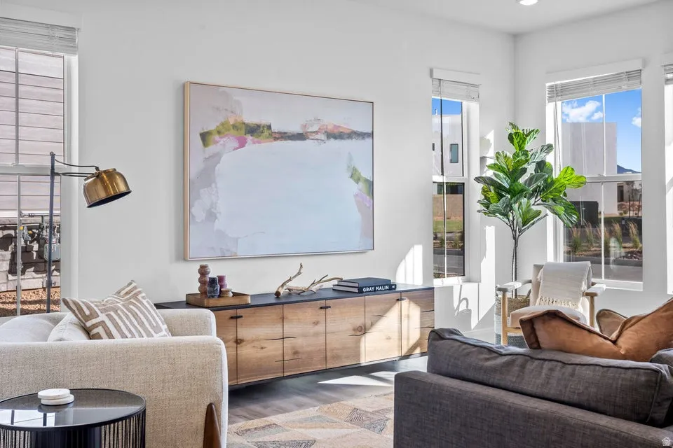 Bright living area featuring high ceilings, multiple large windows, and wood-finish flooring
