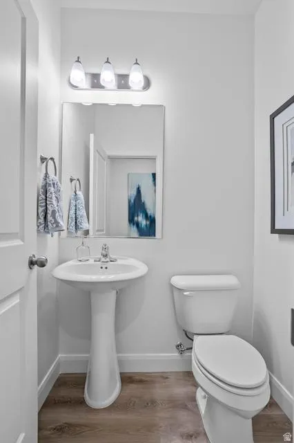 Pedestal sink with chrome faucet, a wall-mounted mirror, and a three-light vanity fixture