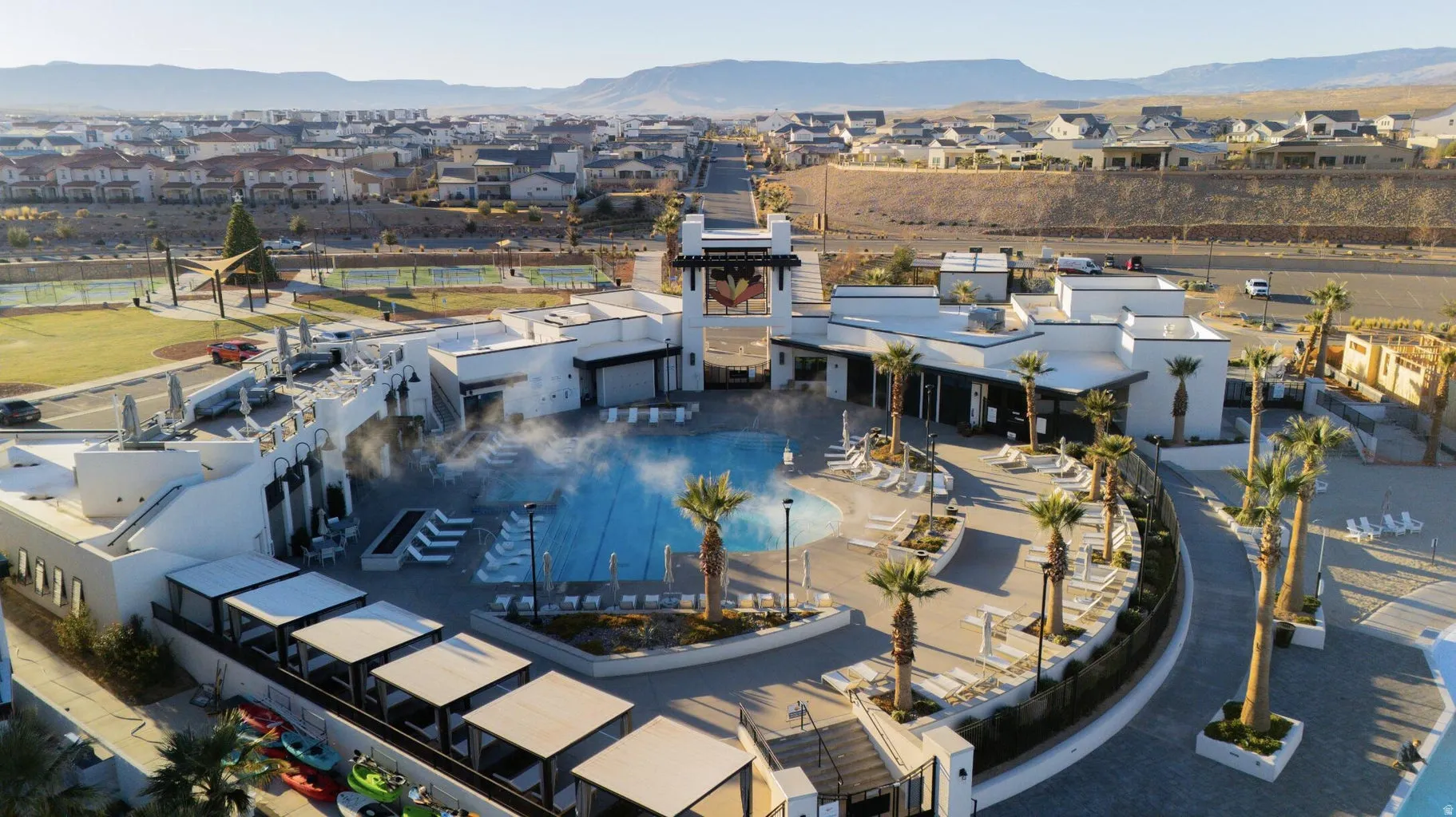 Resort-style pool area featuring multiple lounge chairs, shaded cabanas, and mature palm trees