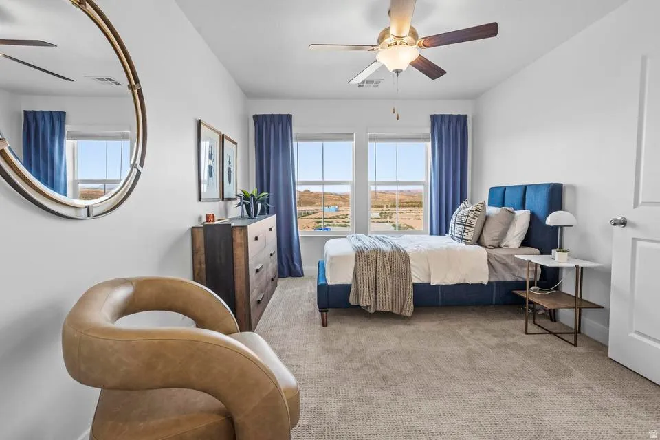 Bright room featuring two large windows, a ceiling fan with light fixture, and plush carpet flooring