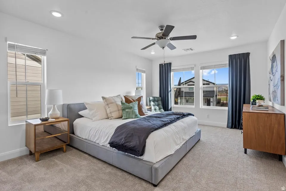Carpeted room featuring a ceiling fan, recessed lighting, and multiple windows with blinds and dark curtains
