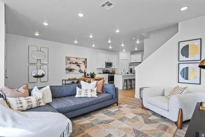 Open-concept living area with recessed lighting, wood-finish flooring, and a stairway featuring a white railing