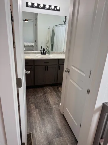 Bathroom featuring a dark wood-finish vanity with a single basin sink, light-toned countertop, and modern black faucet