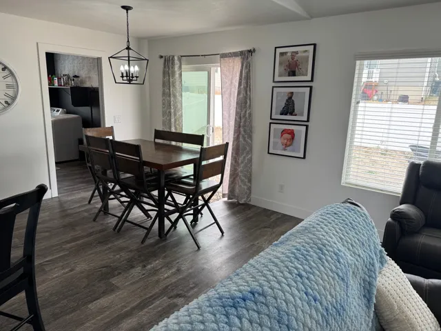 Open dining area with wood-finish flooring, a modern black geometric chandelier, and white walls