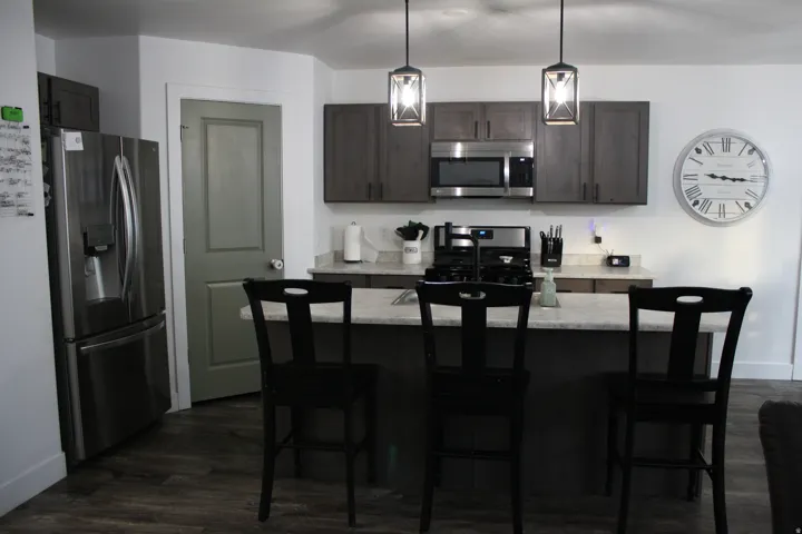 Kitchen featuring dark wood-finish cabinetry, stainless steel appliances, a center island with countertop seating, and pendant lighting