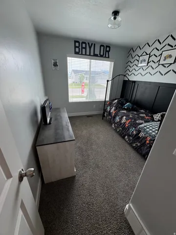 Bedroom featuring a large window with blinds, dark carpet flooring, and a contemporary ceiling light fixture