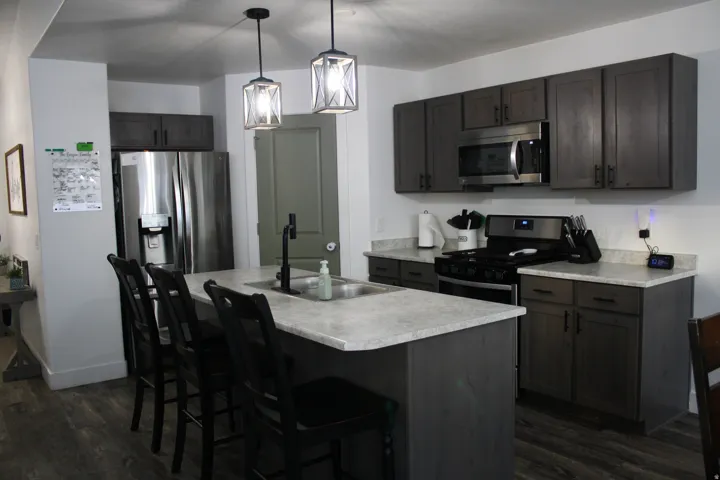 Kitchen featuring dark wood-finish cabinetry, stainless steel appliances, and light-toned countertops