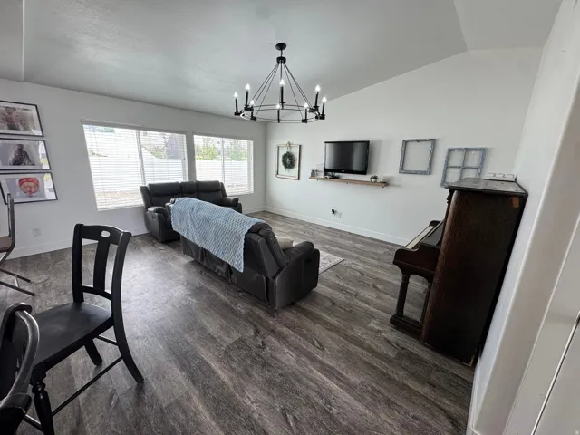 Spacious living area featuring wood-finish flooring, a vaulted ceiling, and ample natural light from multiple windows