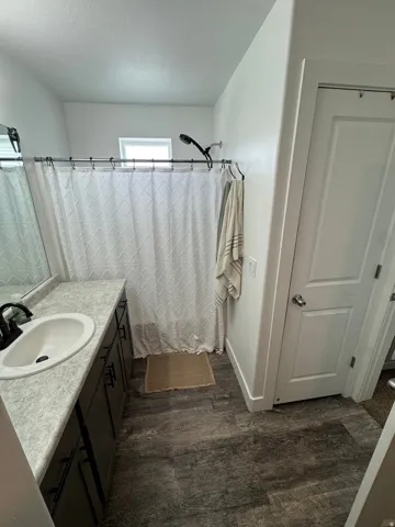 Bathroom featuring a single vanity with an integrated sink, dark wood-finish cabinetry, and a light-toned countertop