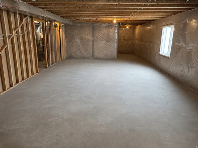 Unfinished basement featuring a poured concrete floor and framed walls