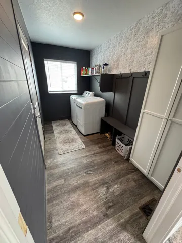 Dedicated laundry room featuring wood-finish flooring and a window with blinds