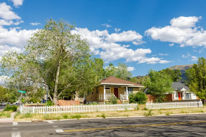 Single-story residence featuring brick exterior, a covered porch with white railings, and a white picket fence