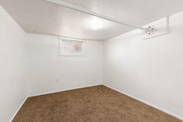 Room featuring light-colored walls, brown carpet flooring, and a single window with white trim