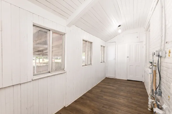 Wood-finish flooring with white paneled walls and a white sloped ceiling