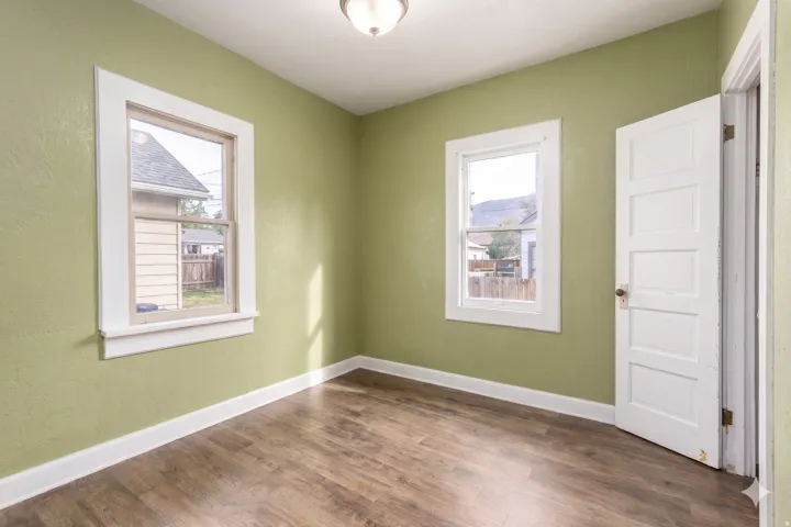 Interior space featuring wood-finish flooring, light green walls, and white trim