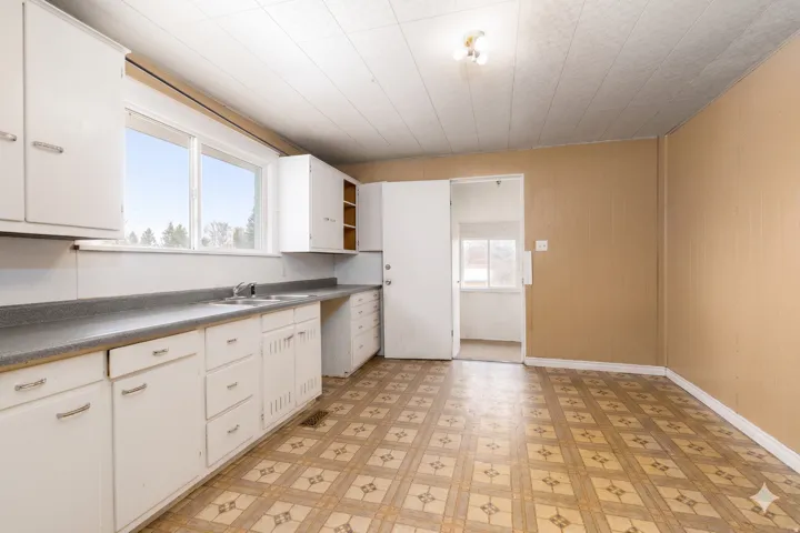 Kitchen featuring ample white cabinetry, a double basin sink, and laminate countertops