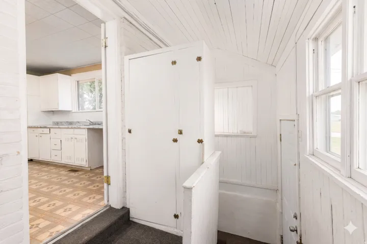 Enclosed porch area with white plank walls and ceiling