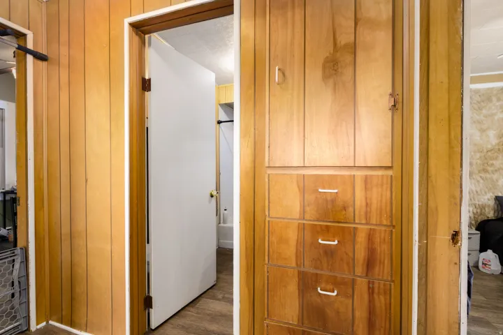 Wood-paneled wall with white trim and a built-in storage unit featuring multiple drawers and a cabinet