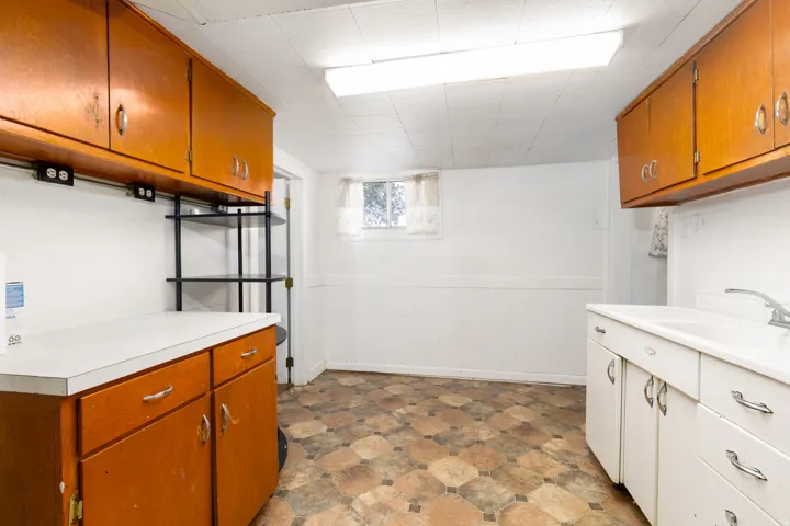 Utility space featuring wood-finish cabinetry, white countertops, and a utility sink