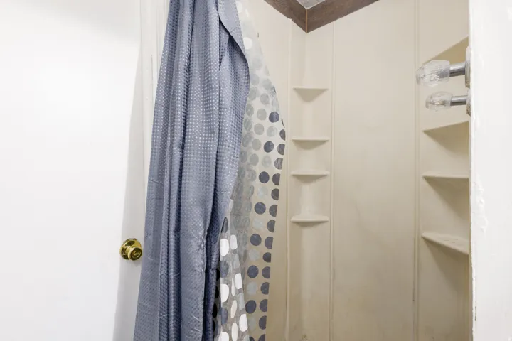 Shower enclosure featuring integrated corner shelving and decorative faucet handles