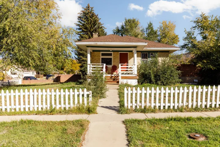 Charming cottage-style home featuring a prominent white picket fence and a covered front porch