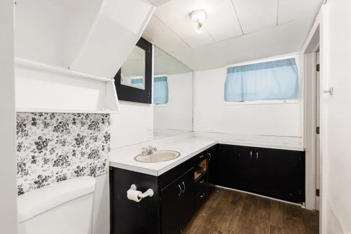 Bathroom featuring a built-in vanity with integrated sink, black base cabinetry, and wood-finish flooring