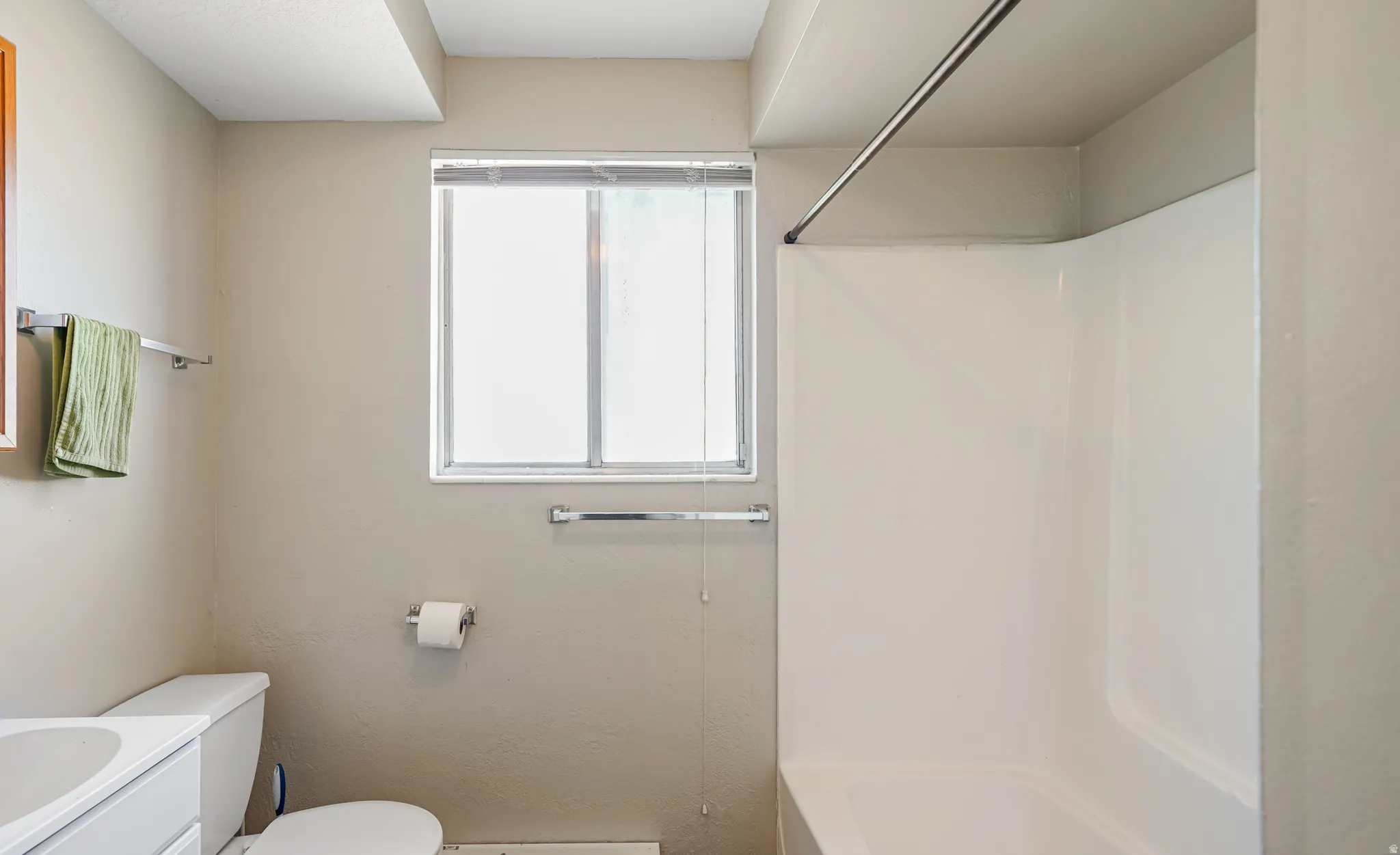 Bathroom featuring a shower/tub combination, single window, toilet, and vanity with an integrated sink