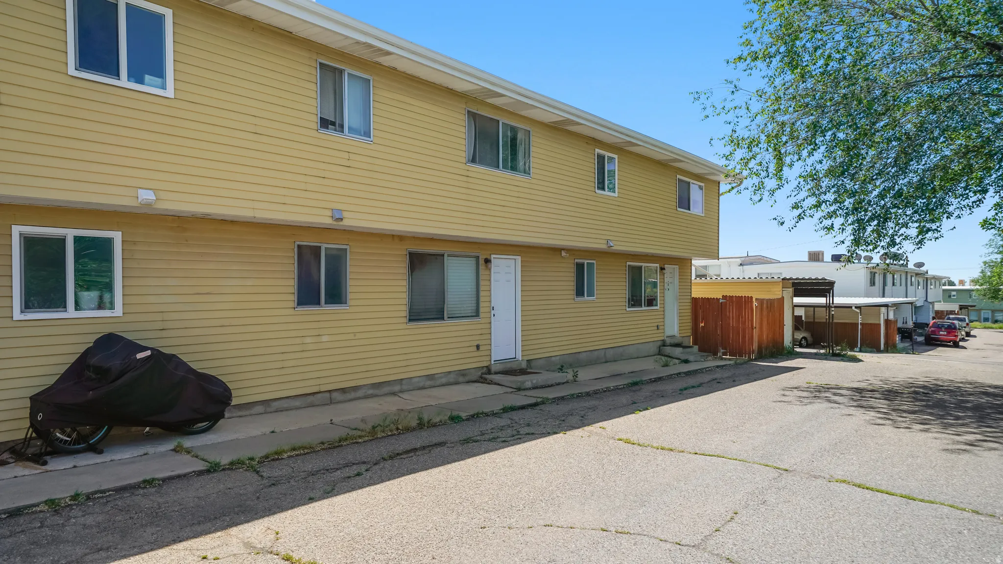 Two-story residential building with light yellow siding and white trim windows