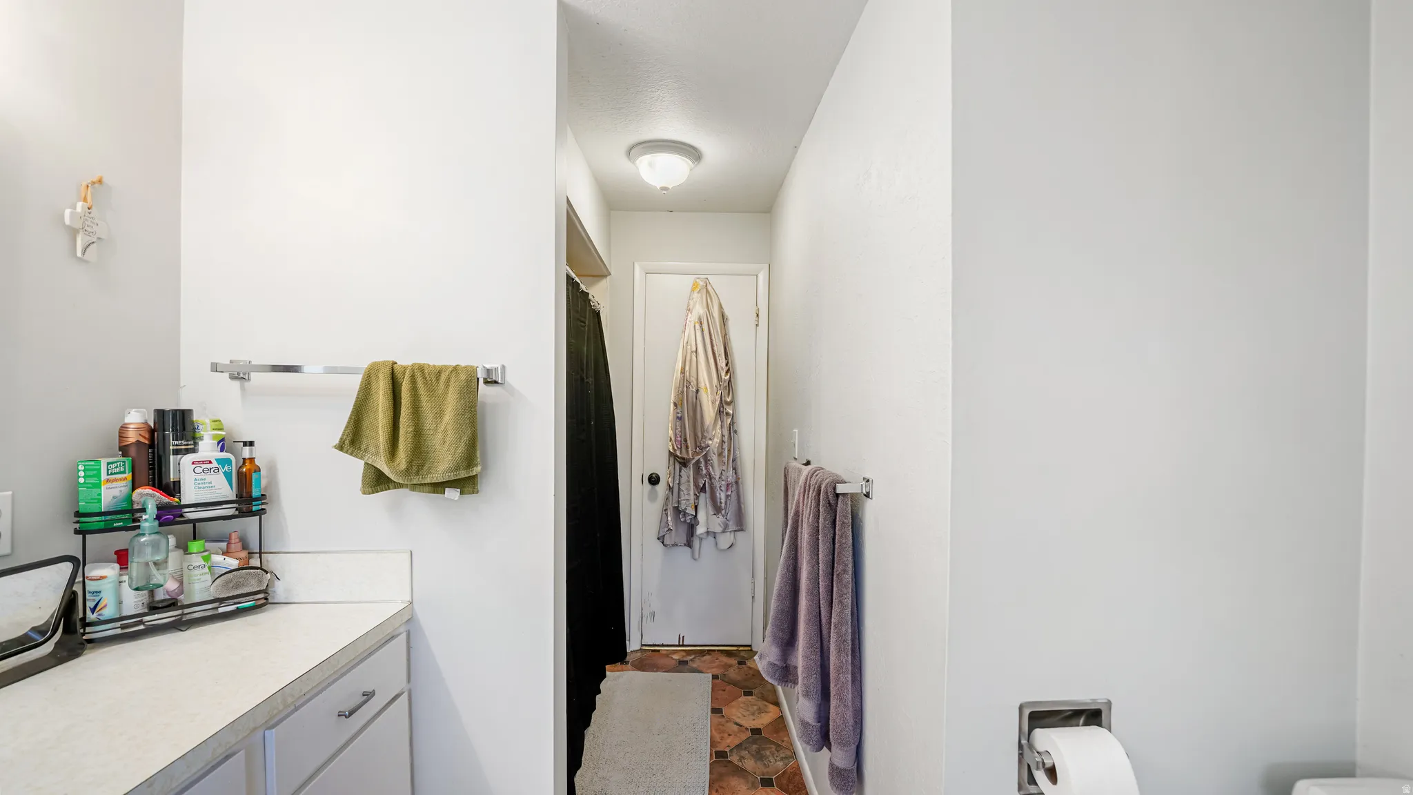 Bathroom featuring a light-colored countertop, white cabinetry with silver-tone pulls, and a built-in towel bar